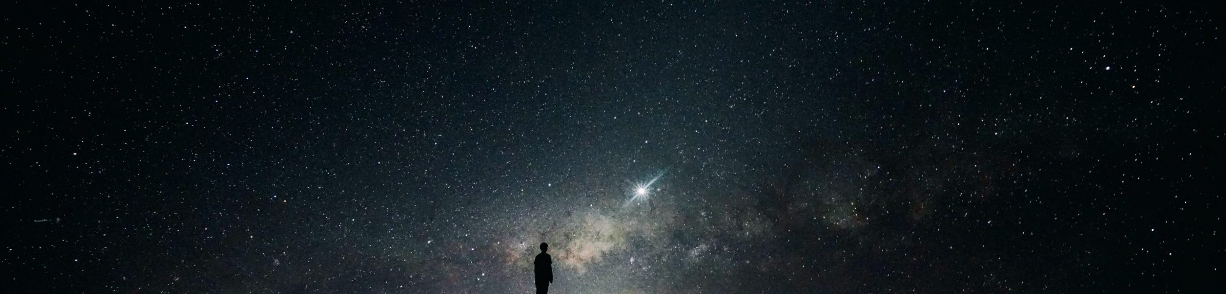 Silhouette of man standing on car in front of night sky